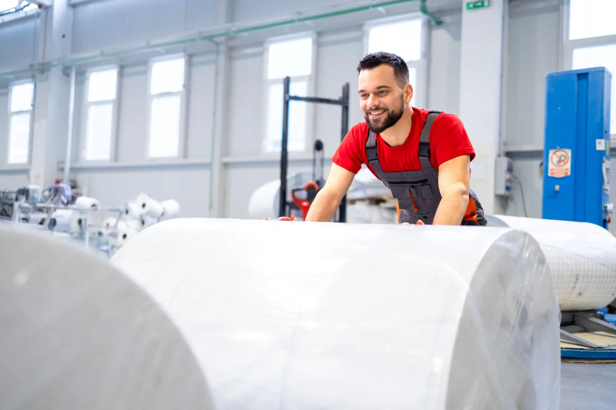 Man working with large industrial paper rolls.